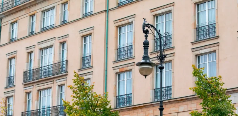 Illustration : façade claire avec garde-corps noirs et lampadaire.