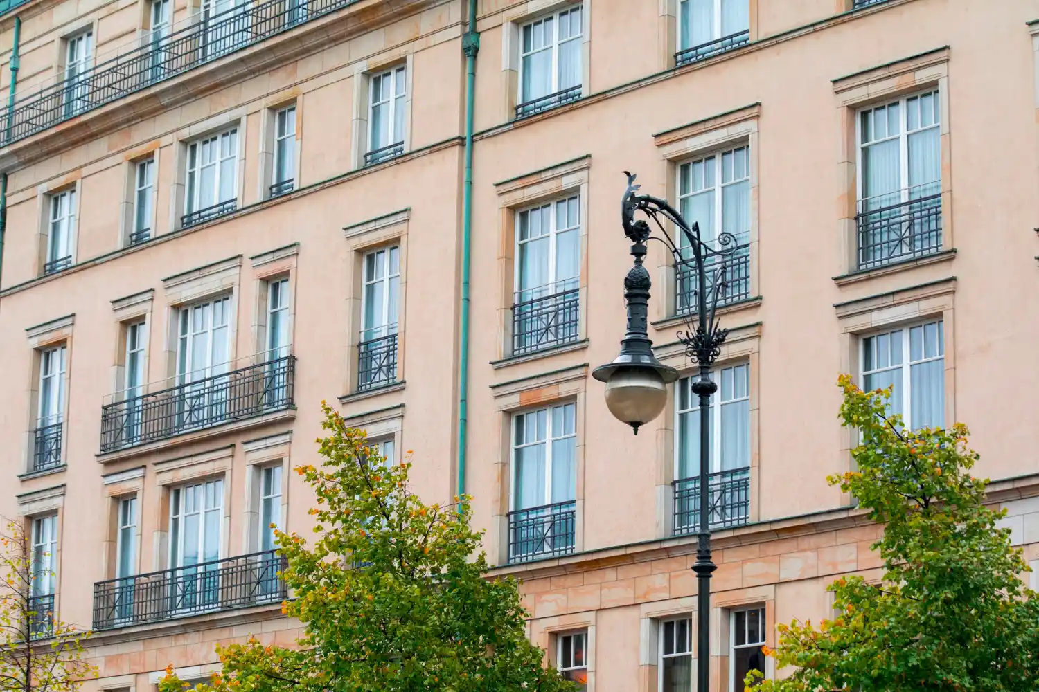 Illustration : façade claire avec garde-corps noirs et lampadaire.