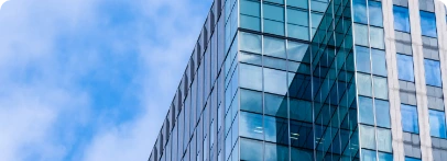 Illustration : façade vitrée d’un immeuble reflétant le ciel et les nuages.