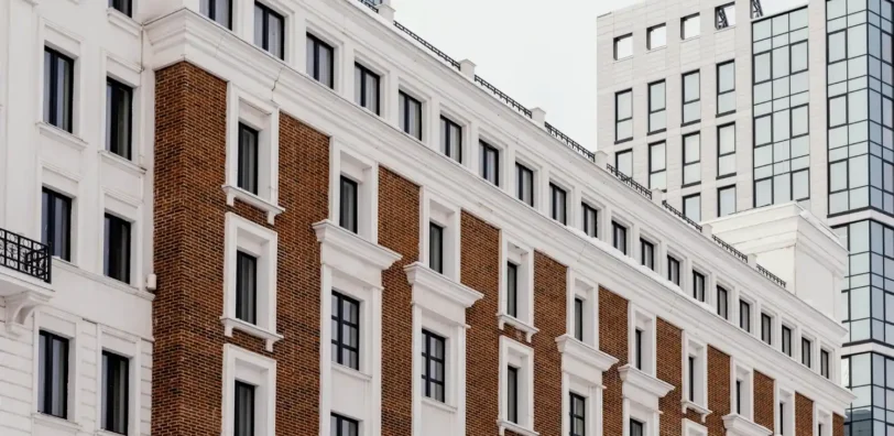 Illustration : façade de briques aux encadrements blancs devant un bâtiment vitré.