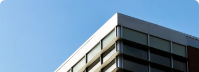 Illustration : angle d’un bâtiment aux grandes baies vitrées sous un ciel bleu.