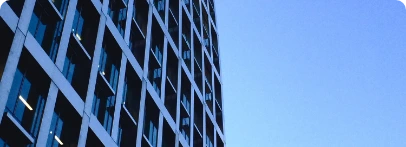 Illustration : façade vitrée quadrillée d’un immeuble sous un ciel bleu.